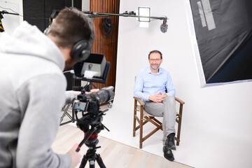 young man video camera operator making interview in professionnal broadcast tv movie studio film production