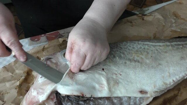 chef cleans cod fish with a knife 