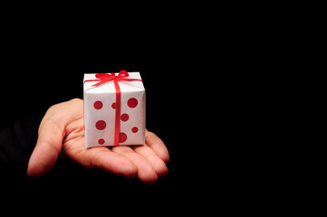 hand holding white present or gift box on black