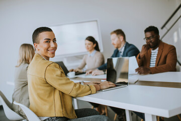 Young short hair business woman sitting in office and using laptop with her team
