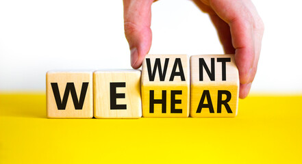 We want and hear you symbol. Businessman turns wooden cubes and changes concept words We hear to We want. Beautiful yellow table white background. Business we want and hear you concept. Copy space.