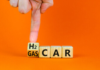 Gas or H2 hydrogen car symbol. Businessman turns a wooden cube and changes words Gas car to H2 car. Beautiful orange table orange background copy space. Business and gas or H2 hydrogen car concept.