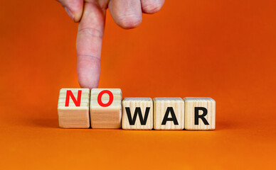 No war symbol. Businessman turns cubes and changes concept words War to No war. Beautiful orange table orange background. Business and no war concept. Copy space.