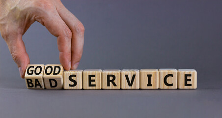 Good or bad service symbol. Businessman turns cubes and changes words bad service to good service. Beautiful grey table grey background. Business good or bad service concept, copy space.