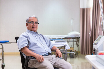 Obraz premium Happy optimistic senior 70s man looking at camera with smile during appointment at doctor office. Portrait of elder male patient in background. Medic care