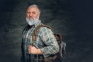 Elderly tourist man with bag posing against dark background