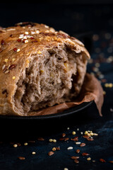Cereal bread, parchment paper is on the table, dark background