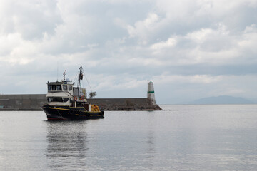 Black ship on sea. There is lighthouse at back. Empty space for text. 