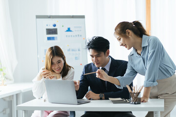 Cheerful asian people colleagues working together sit at desk look at computer screen discuss new project search solutions joking to increase effective communication concept, chart on whiteboard.