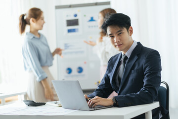Closeup of three diverse business people listening to senior business leader who is explaining something to them with blurred lounge view in background. Two colleagues are sitting back to camera.
