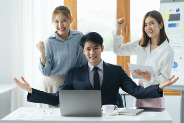Fototapeta premium Group of three business partners discussing new project at meeting in office room, using laptop. Middle aged businessman explaining idea showing presentation on laptop screen. Business success