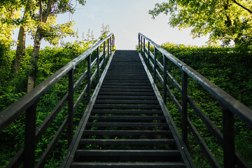 Outdoor wooden staircase in the woods in the sunny summer day.