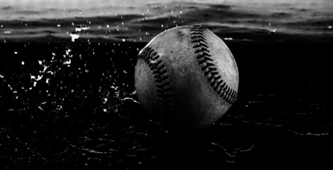 Rain out concept with water splash on old baseball ball close up.