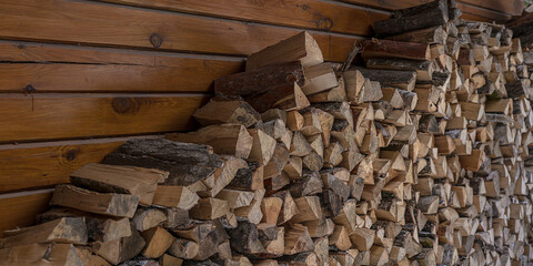 Firewood in stack at backyard near barn wooden wall of farm. Ecological biofuel conception.