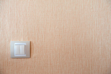 Light switch on the background of a beige textured wall.