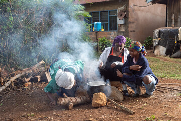Older African Woman helping young teenage girls to  prepare a pot of tea