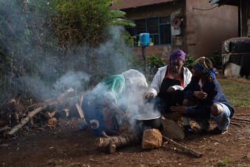 Older African Woman helping young teenage girls to  prepare a pot of tea