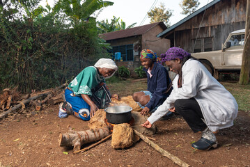 Older African Woman helping young teenage girls to  prepare a pot of tea