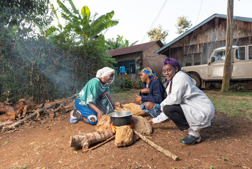 Older African Woman helping young teenage girls to  prepare a pot of tea