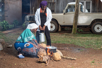 Older African Woman helping young teenage girls to  prepare a pot of tea