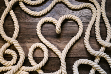 Symbol heart made of rope on a wooden background - obrazy, fototapety, plakaty