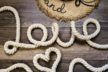 Inscription love and symbol heart made of rope on a wooden background