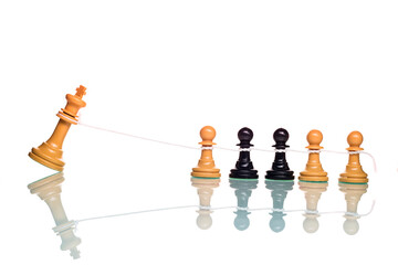 Chess pawns overthrowing the white king with a rope.