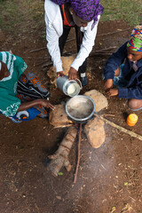 Young African teenager pouring fresh milk into pot 