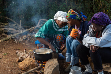 Older African Woman helping young teenage girls to  prepare a pot of tea