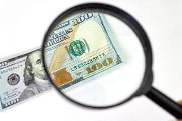 Magnifying glass on dollar banknotes. Magnifying glass on a pile of 100 dollar banknotes