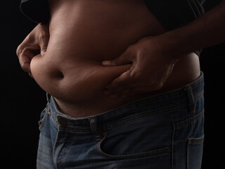 Naklejka premium Fat man squeeze the stomach on black background. Health care concept.