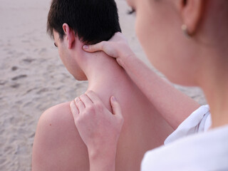 a young chiromassage therapist giving shoulder and neck massages to a young man on a beach in Valencia.
