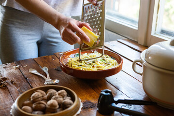 Woman grates cheese to the plate with fresh pasta