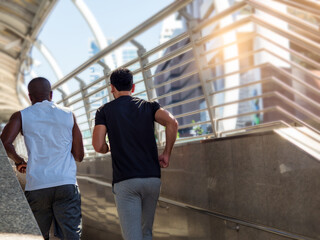 Rear view of two diverse men jogging in the city.