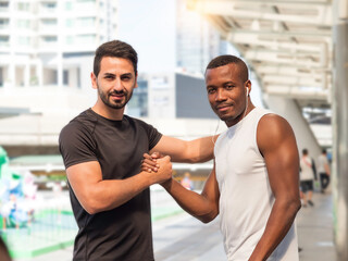 Two diverse athletes smiling, looking at camera and giving strong hands shake.