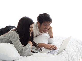 Man and woman lying on bed watching movie from notebook together. Asian couple browsing internet on laptop.