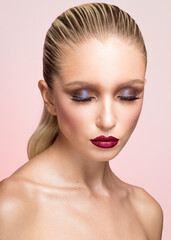 Fototapeta premium Closeup beauty portrait of young woman with makeup, hair straightened and caught in the back, isolated pink background.