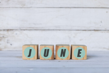 june concept written on wooden cubes or blocks, on white wooden background.
