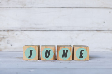 june concept written on wooden cubes or blocks, on white wooden background.