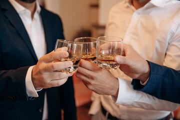 Friends cheers of the whiskey glass in wedding. Man whiskey and friendship