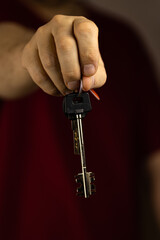 A man holds out the keys in his hand. Vertical photo