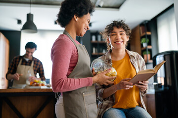 Happy african american mother helps teenage daughter with homework using digital tablet