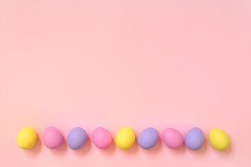 Top view layout of colorful painted Easter eggs on pink background. Greeting card, poster, banner for Happy Easter. Copy space for your text.