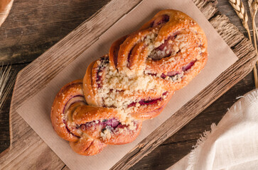 Fresh baked goods - delicious wicker bun on wooden background
