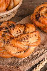 Fresh baked goods - delicious wicker buns with poppy seeds on a wooden