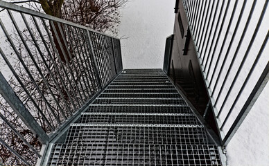 Ażurowe schody , ze stali ocynkowanej , z poręczami i szczebelkami z metalu - zimą w śniegu .