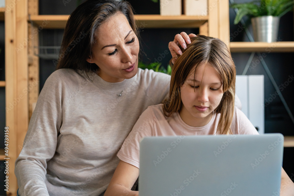 Wall mural happy young asian single mother studying with teenage child girl using laptop at home schooling