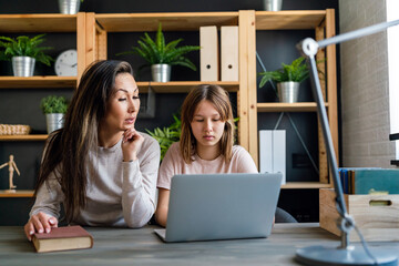 Single mother helping his teenager daughter in homeschooling. People, family technology concept.