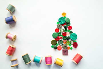 Tree made of buttons green, red color. Multicolored threads with wooden spools. White background, copy space. Creative Christmas concept, or gardening