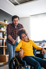 Child with disability in wheelchair at home having fun with father. Multiethnic happy family concept